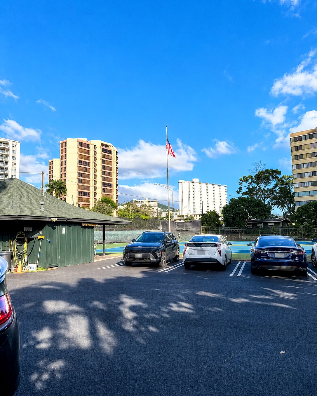 On-site parking at Beretania Tennis Club with the courts and an American flag beyond